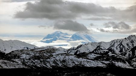 A snowy mountain range under a cloudy sky.