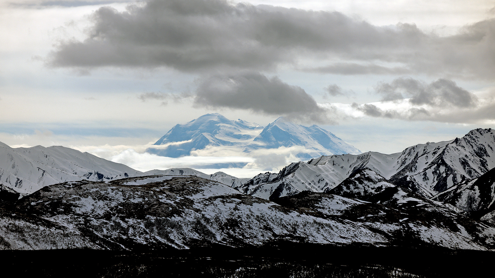 A snowy mountain range under a cloudy sky.