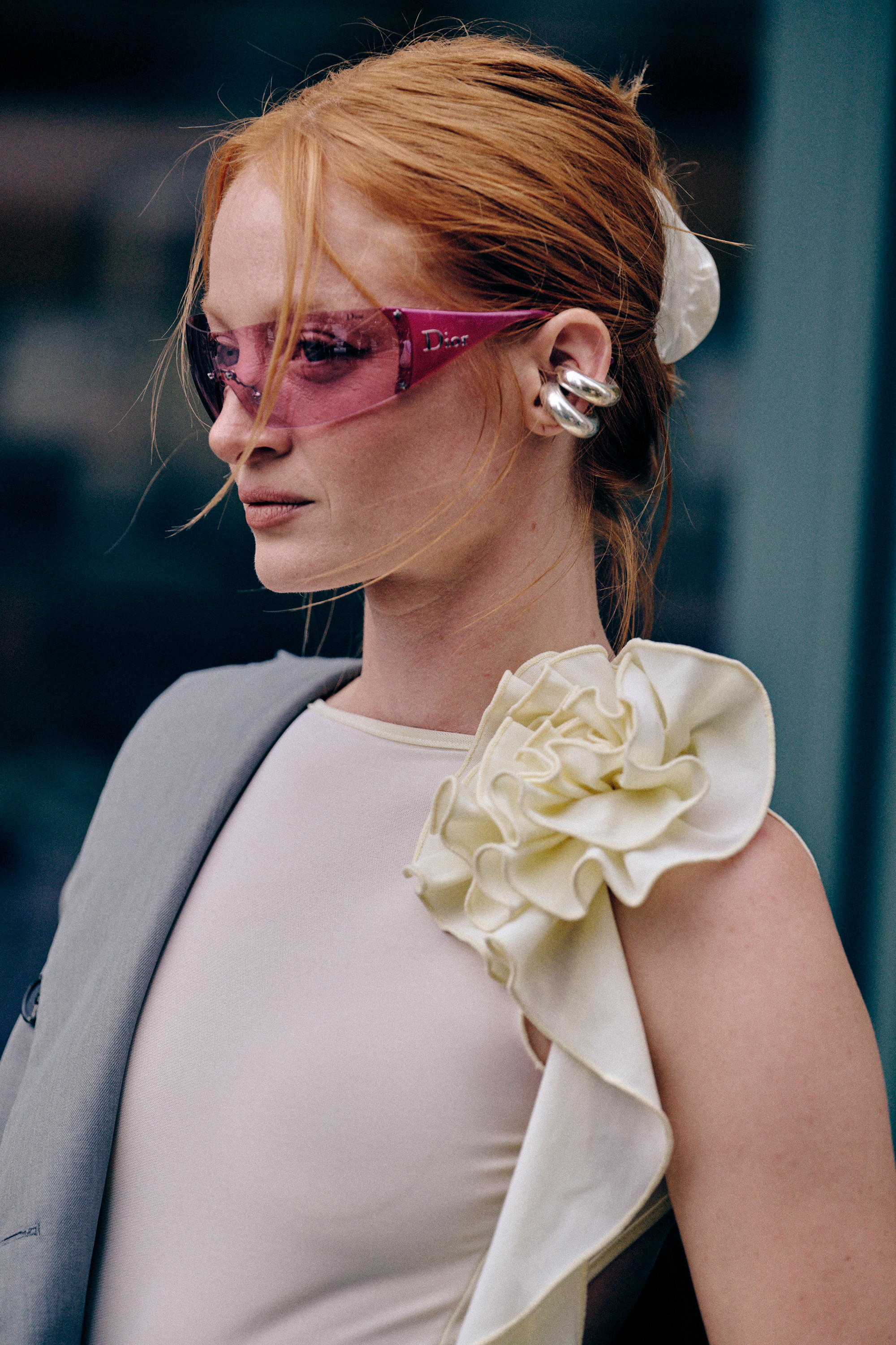 a woman wearing pink y2k sunglasses and a white flower blouse and gray blazer