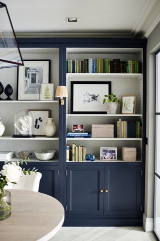 Blue cabinet with white shelving, lamp and round wooden table