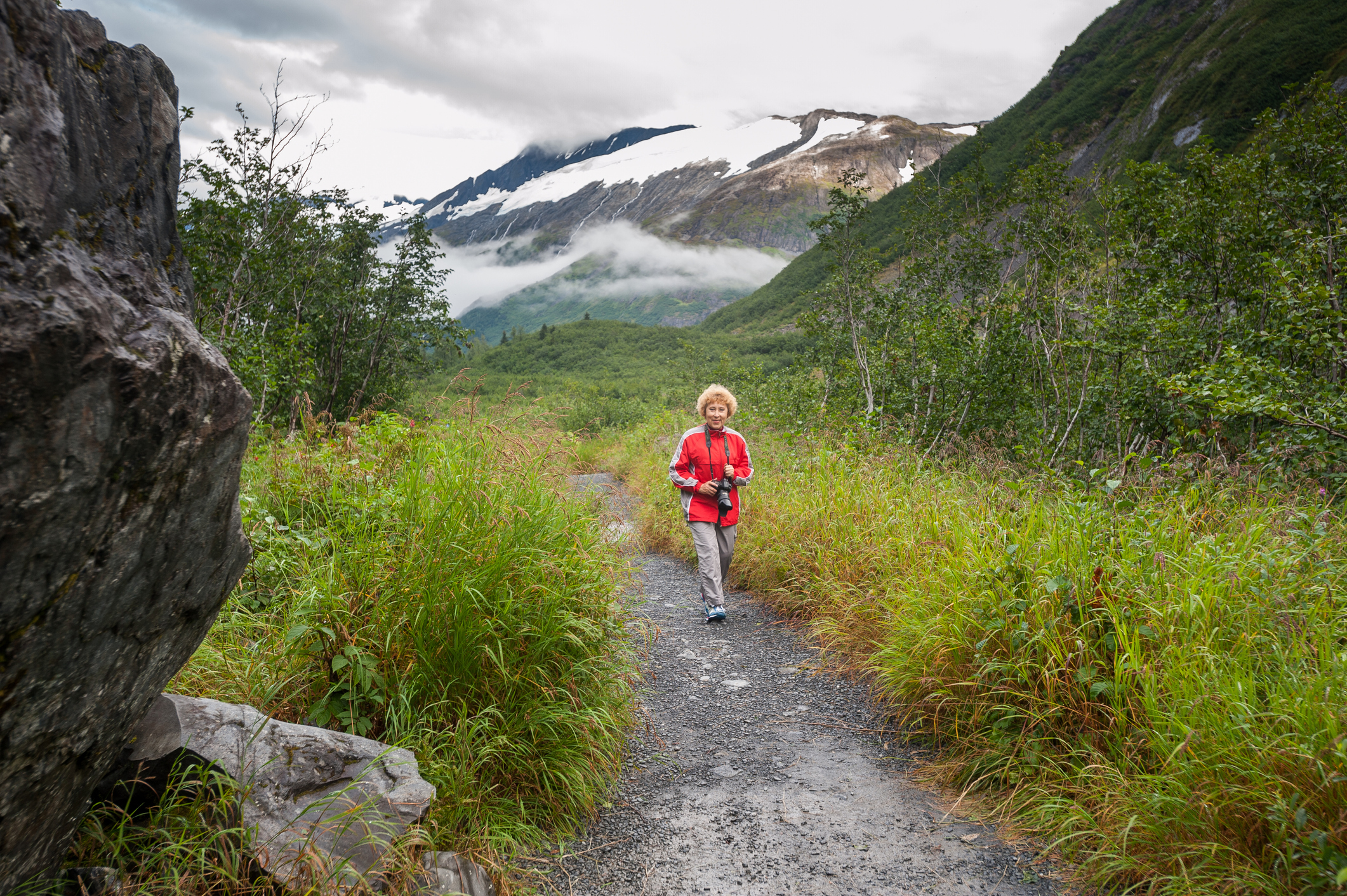 An Alaskan senior hiking, with the mountains in the background.