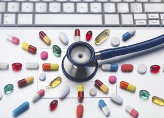 Pills and stethoscope on laptop