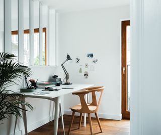 small office area divided by white half height wall with white vertical strips of wood acting as screen on top half of wall