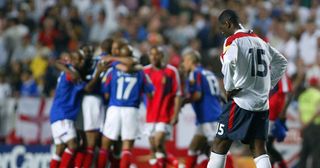 England defender Ledley King (R) looks dejected as the French team celebrate after winning their opening football match 2-1, 13 June 2004 at the Estadio da Luz in Lisbon. France and England are competing in Group B with Switzerland and Croatia.