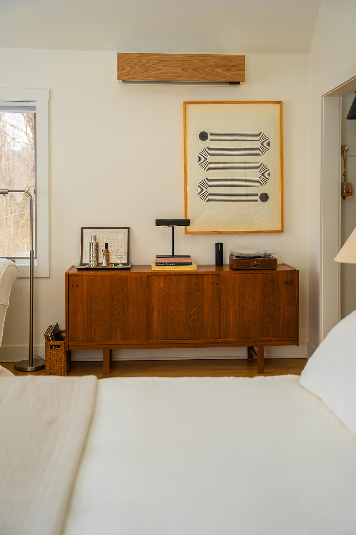 A bedroom with a Quilt ductless HVAC system clad in wood, hanging above a dresser.