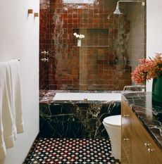 a bathroom with a black marble bathtub and a red tiled wall