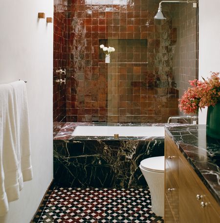 a bathroom with a black marble bathtub and a red tiled wall