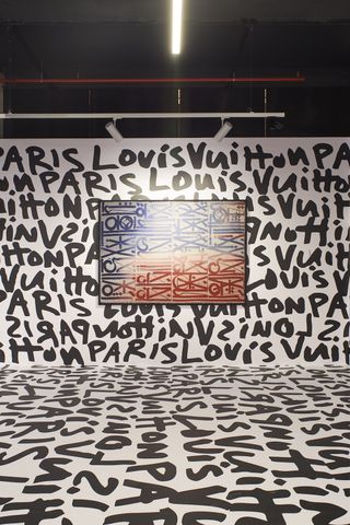 Louis Vuitton written on walls and floor of gallery with picture on wall