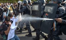 A policeman pepper sprays demonstrators in the capital, Brasilia, on June 15.