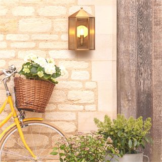durable brass wall light by stone house with yellow bike