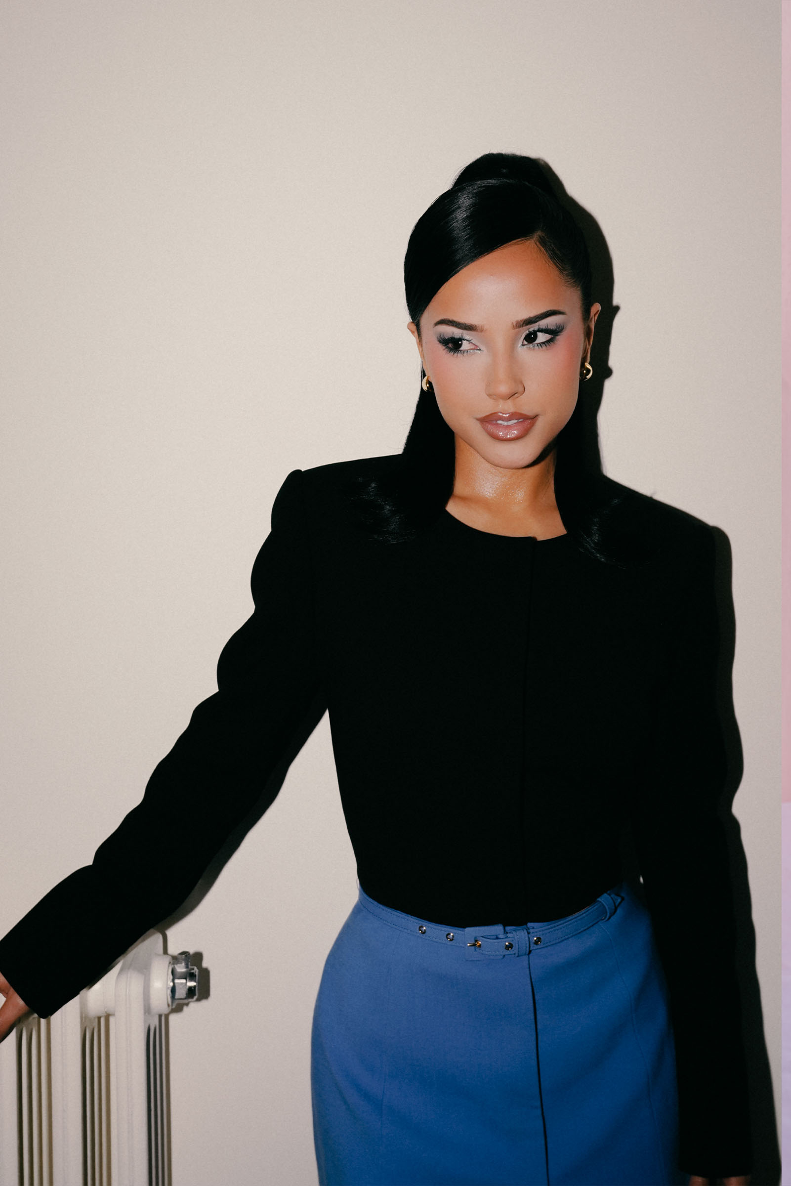 Beck G in Madrid before the Carolina Herrera show. She is wearing a black long-sleeve top and blue shorts.
