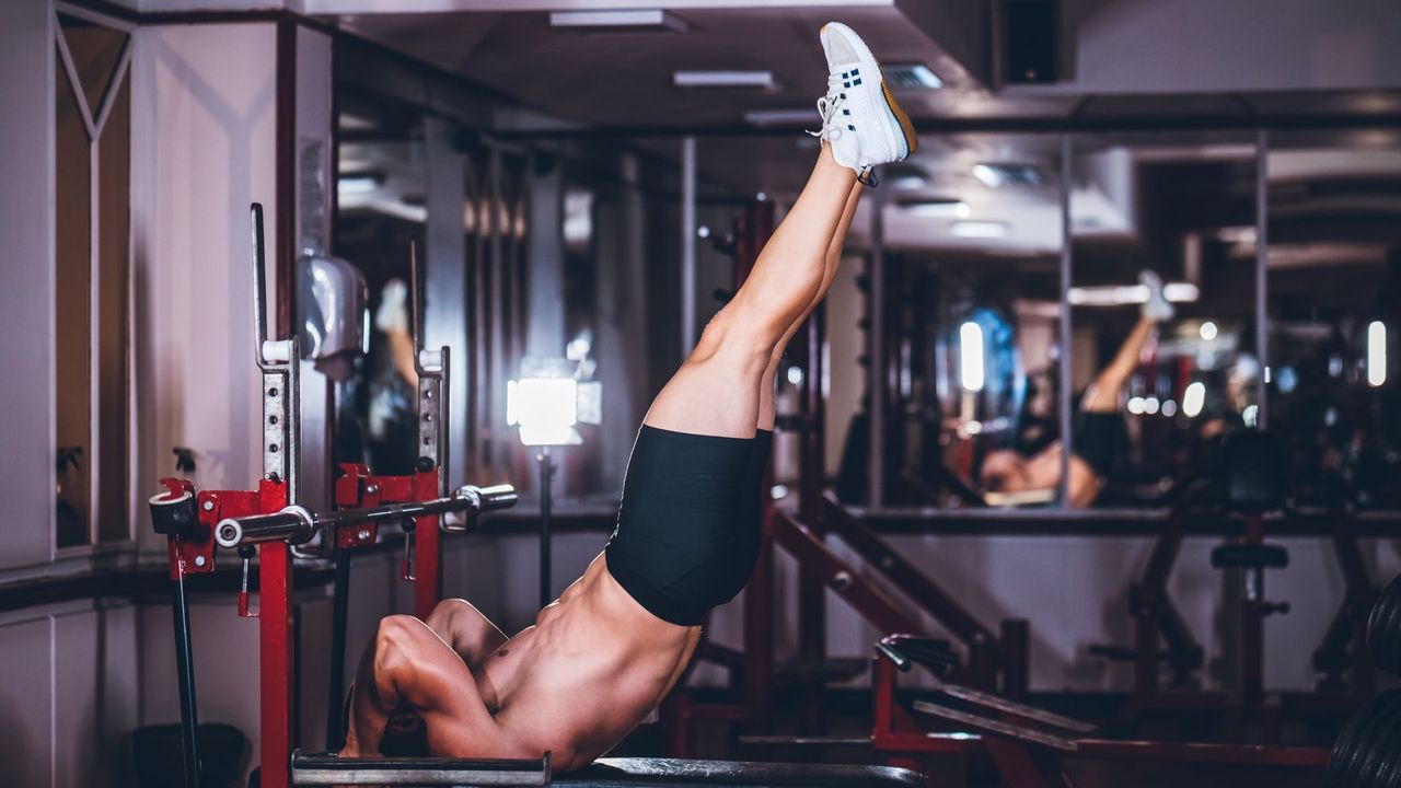 Man performing dragon flags on a weight bench