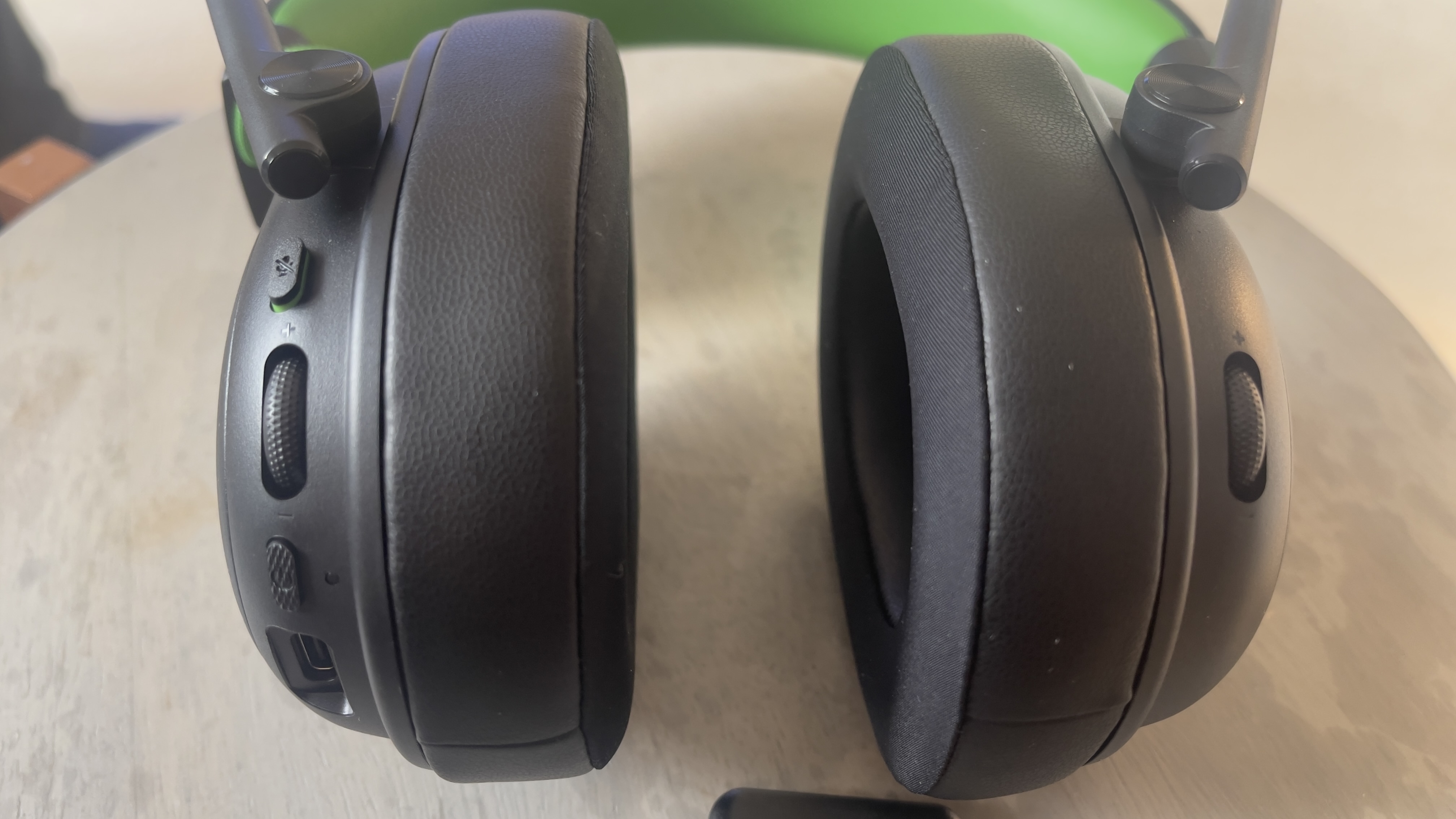 The Razer Blackshark V3 X gaming headset on a table. A living room is visible in the background.