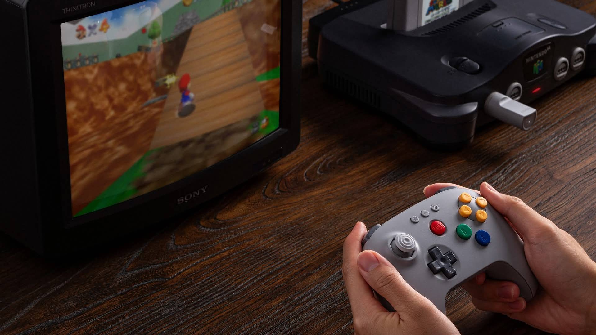 Hands using 8Bitdo N64 controller 2.4G with Nintendo N64 connected to Sony CRT TV with Super Mario 64 on screen.