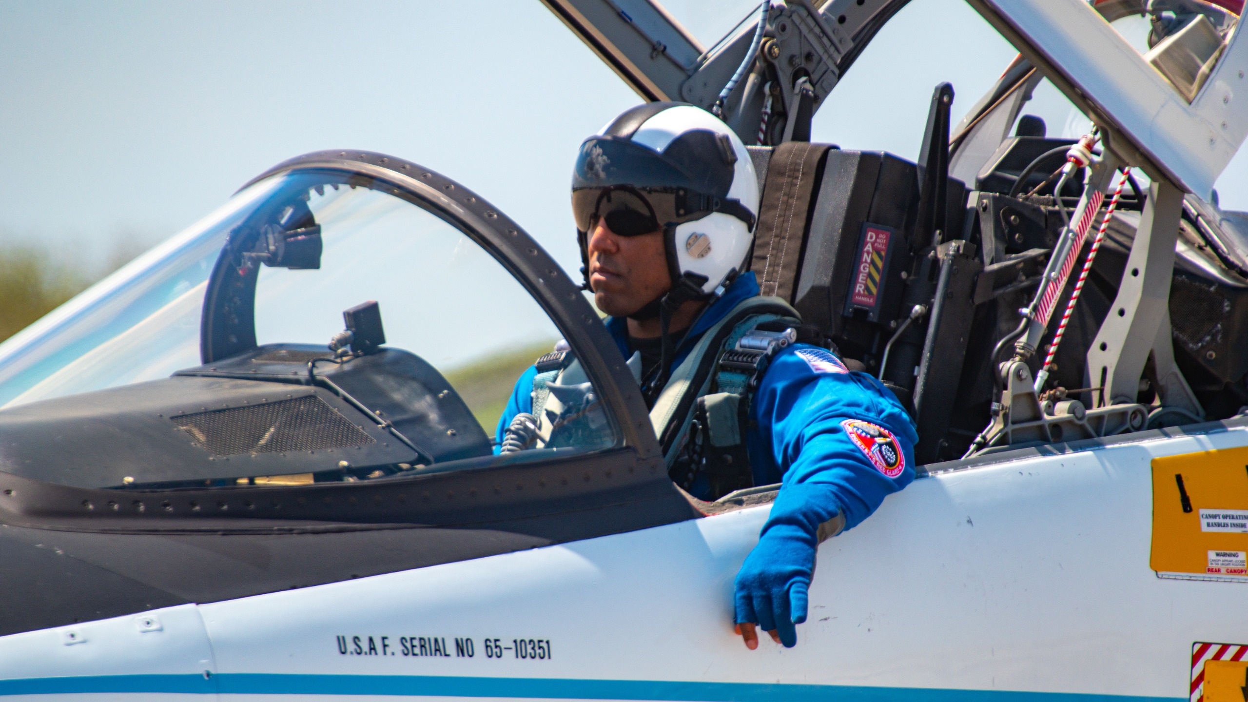 A man in a blue jumpsuit sits in an open jet