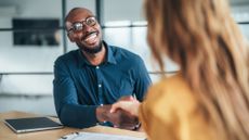 A smiling financial adviser shakes the hand of his client.