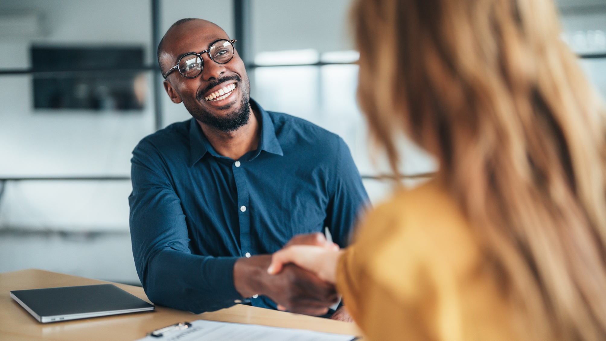 A smiling financial adviser shakes the hand of his client.