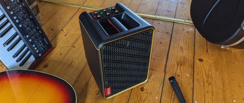 A Positive Grid Spark Edge on a wooden floor with acoustic guitar, microphone, and synthesizer