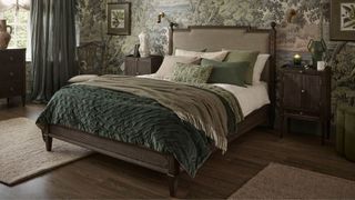 A dark wood bed in the middle of a bedroom with green wallpaper