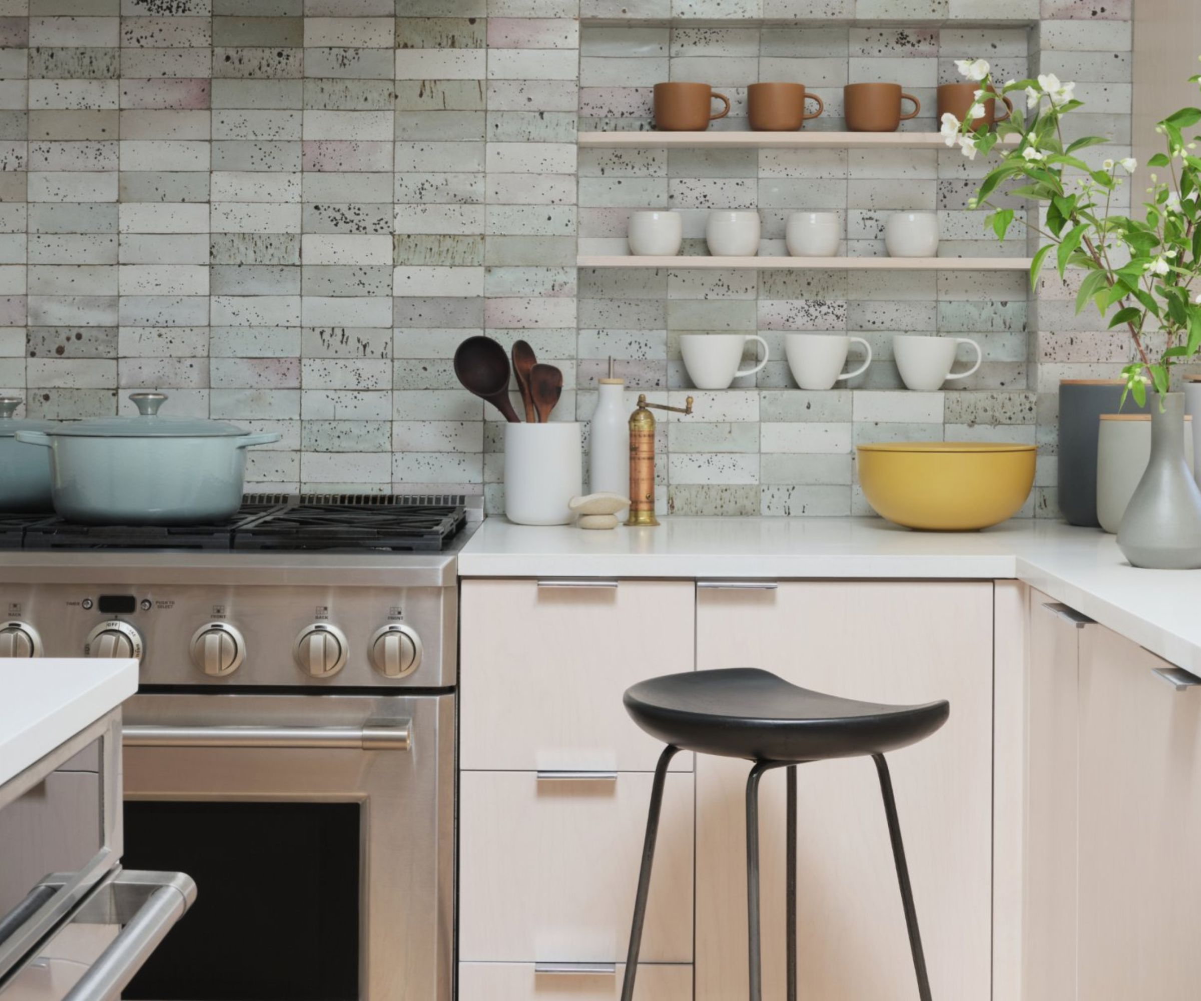 A coastal West Elm kitchen with pink cabinets, chrome hardware, and gray wall tiles