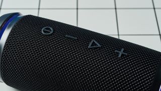 a black portable bluetooth speaker with LED panels sits atop a white table with a blue background