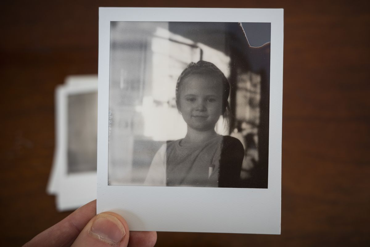Polaroid SX70 instant print in the hand, black and white portrait