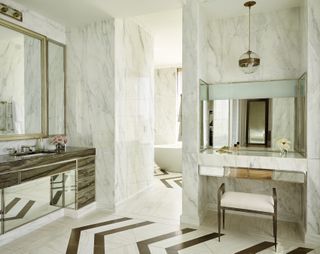 marble bathroom with cabinets, vanity, mirror, marble flooring