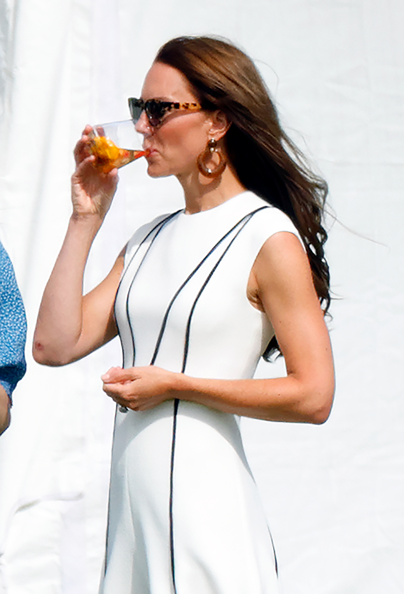 Princess Kate wearing a white dress drinking from a glass