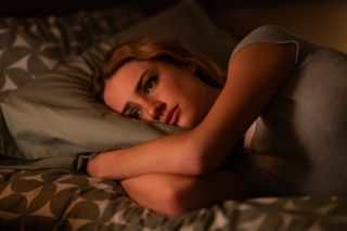 Grace Van Patten as Lucy, lying on a bed with her arms folded under the pillow, in the second season of 