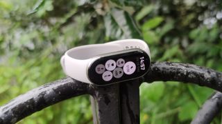 The Xiaomi Smart Band 9 on a man's wrist in front of a green park.