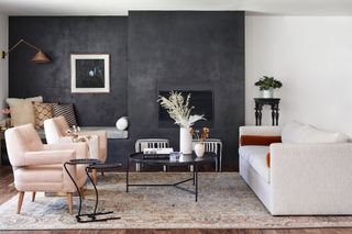 A sitting room with a black feature wall containing a fireplace.
