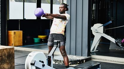 A man performs a kettlebell swing in his home gym