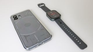The CMF Watch Pro next to the Nothing Phone (2) facing down