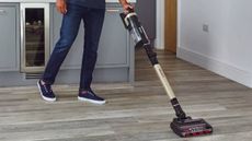 A person using a cordless vacuum in their kitchen from Shark Clean.