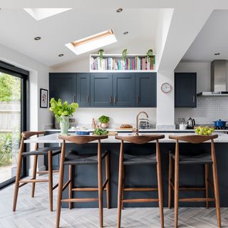 large kitchen with dark cupboards and large island surrounded by brown and black stools
