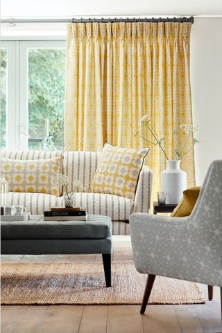 Living room with a muted yellow colour scheme and striped sofas and patternsd cushions as an example of how to mix patterns and prints in interiors by vanessa arbunthnott