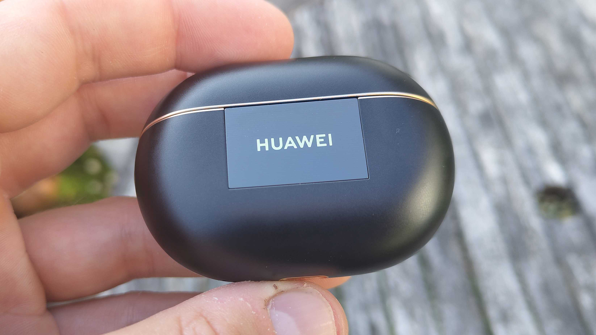 Huawei FreeBuds Pro 4 in-ear headphones case held in hand showing Huawei logo