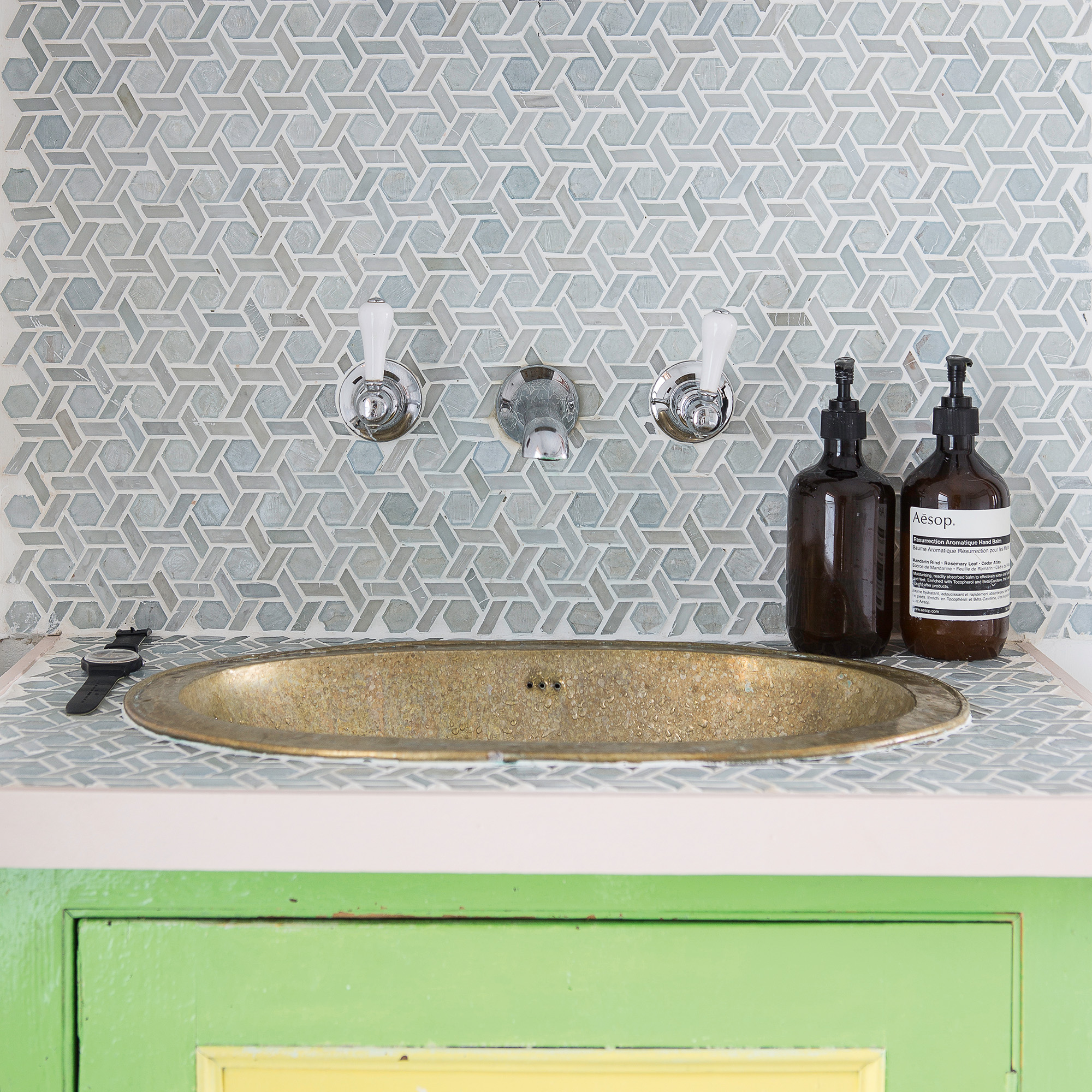 blue and grey mosaic tiles on walls and worktop with green cabinetry