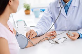 A woman gets her blood pressure checked by a doctor.