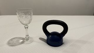 Tempur-Cloud mattress review image shows a wine glass placed next to a black weight during a motion isolation test