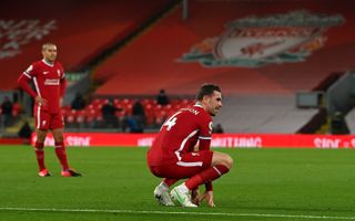 Jordan Henderson crouches on the pitch after his injury against Everton