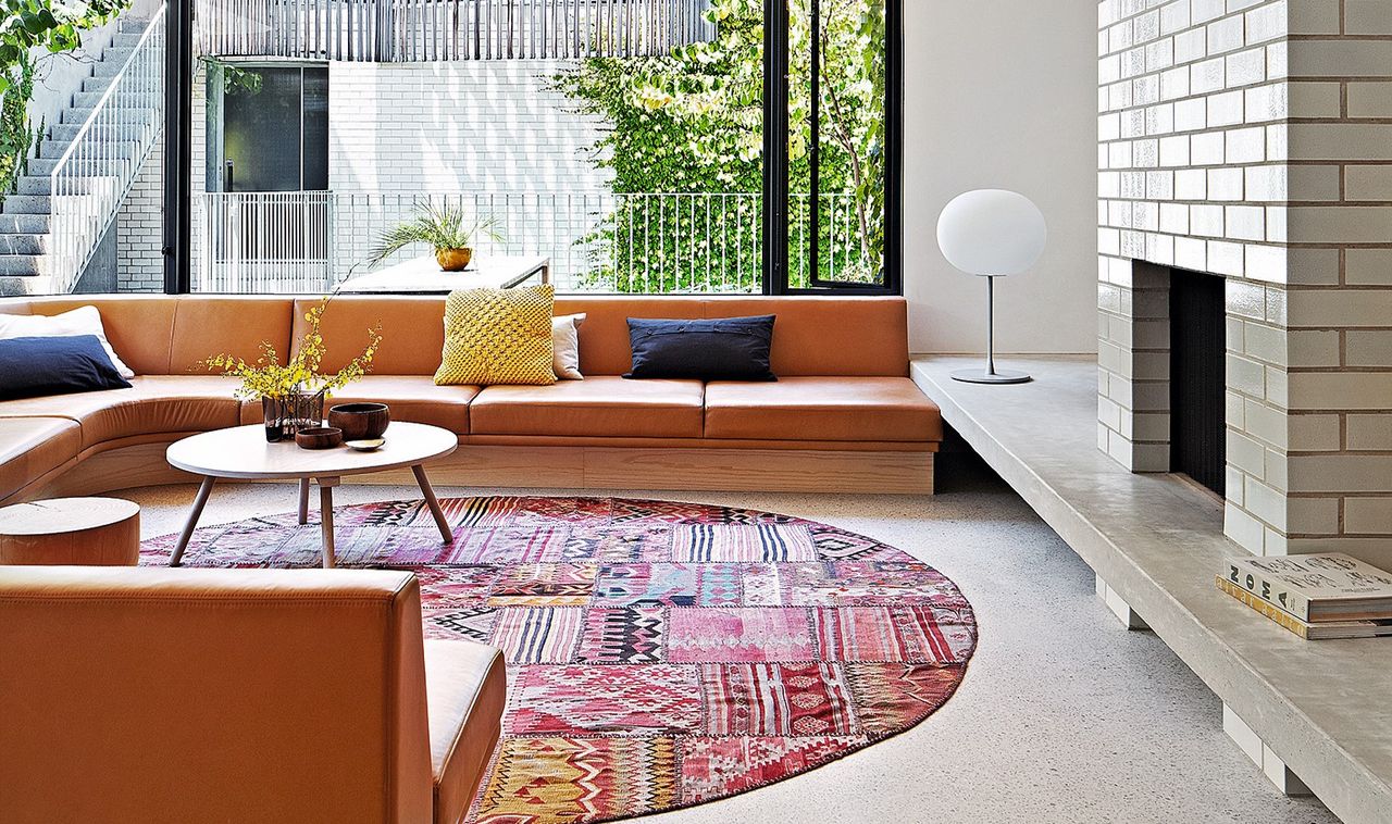 A living room with a patterned rug, and built-in round seating