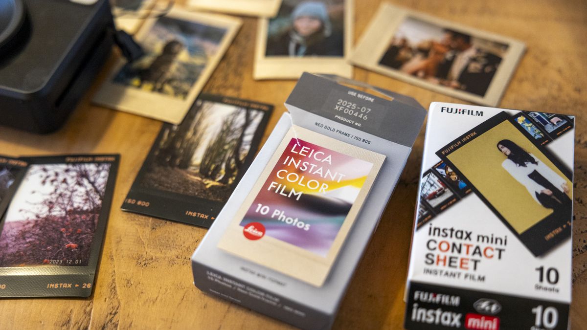 A wooden table covered in Instax Mini prints and film boxes