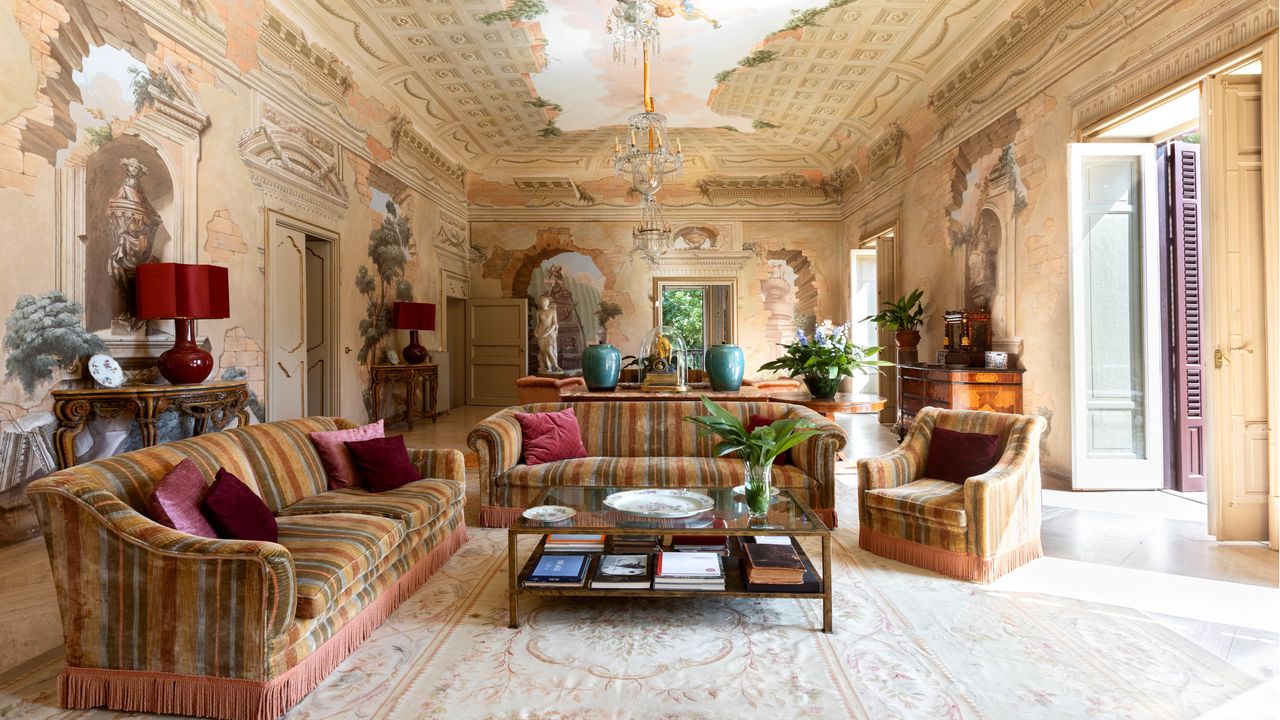 grand living room with large patterned sofas, shuttered windows, glass coffee table, vintage Italian decoration