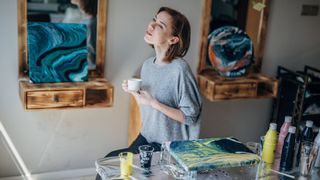 A lady stands between her acrylic marble paintings