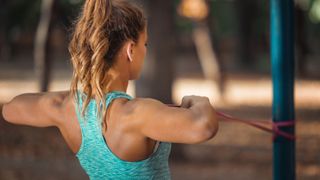 Tricep and chest workout: Image shows woman using resistance band on pole, pulling it towards her