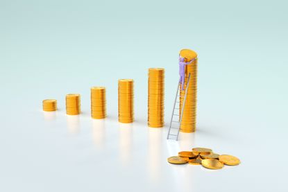 Stacks of gold coins are arranged in financial levels by people on a light blue background with copy space.