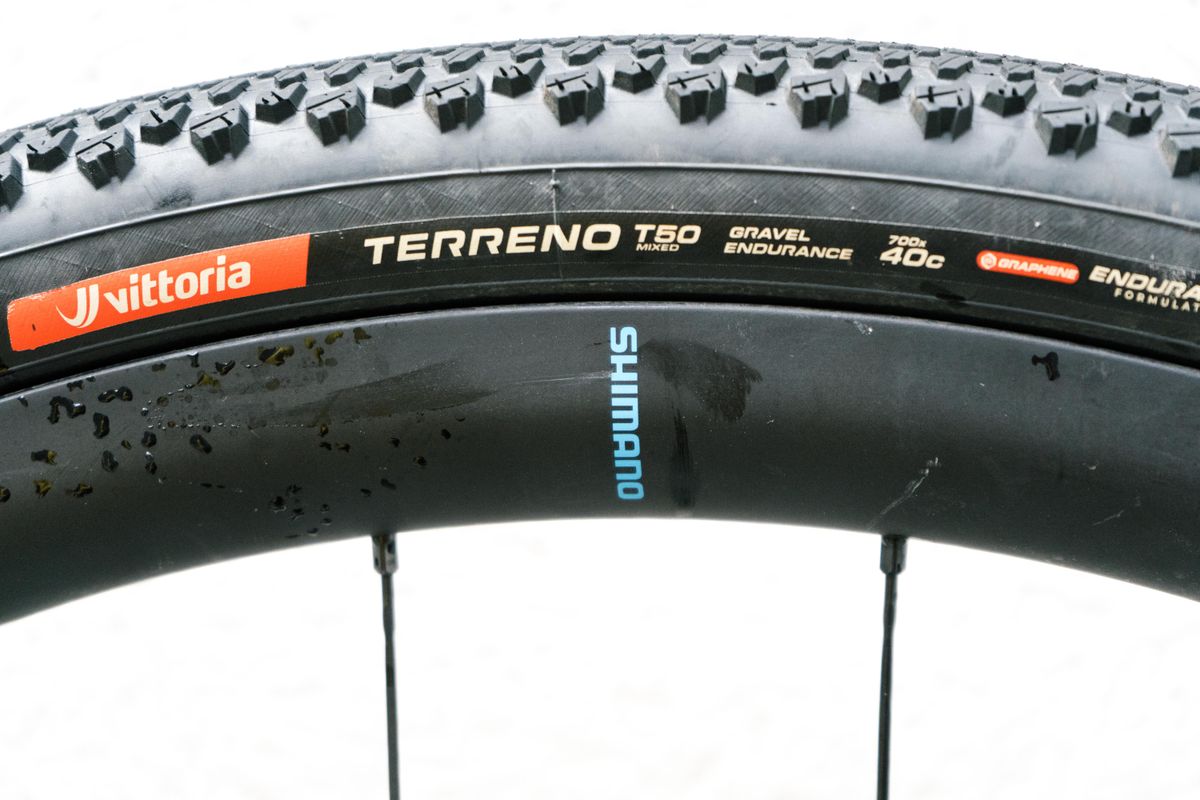 The rear wheel of a gravel bike against a white wall
