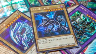 YuGiOh cards on top of each other including Red-Eyes Black Dragon, Blue-Eyes WHite Dragon, Dark Magician Girl and others