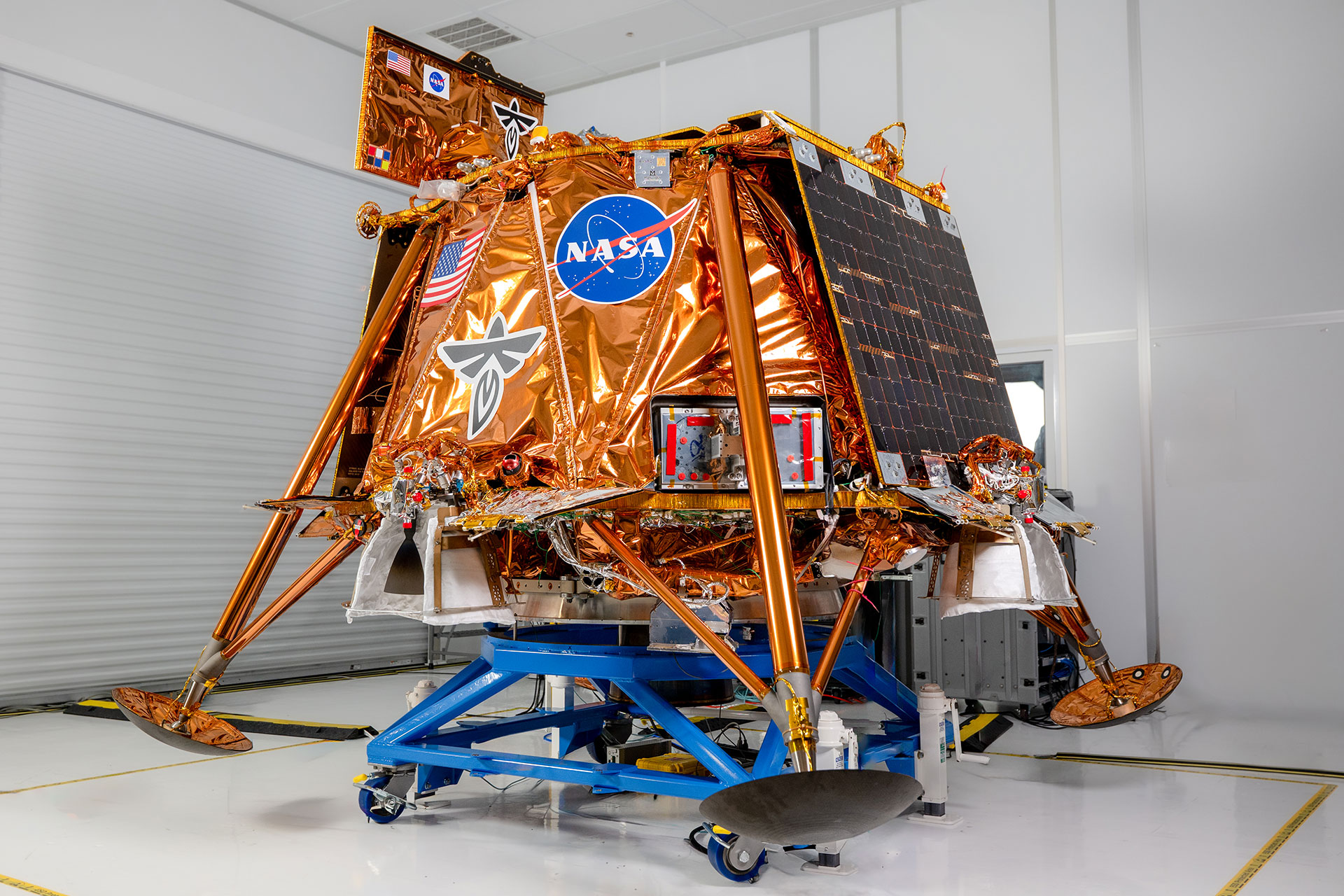 a robotic lunar lander sitting on a wheeled dolly in a clean room prior to its launch